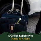 Blue suitcase with a coffee package attached, parked next to a car.